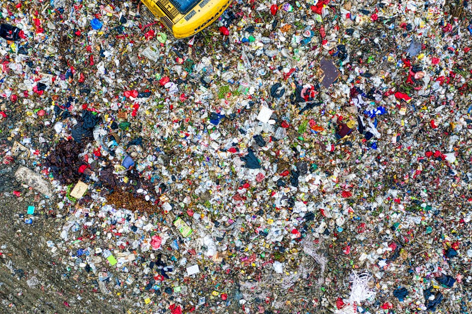 A large pile of black rubbish bags, likely filled with household waste, stacked against a modern exterior wall composed of large, light-colored square tiles. Some bags are partially torn or bulging, revealing mixed contents such as plastic bottles, paper, and other refuse; a few bottles are visible outside the bags on the ground. Behind the pile, a graffiti tag in red spray paint reads 'XEND' on the tiled wall. The scene appears to be outdoors in an urban environment with cloudy skies visible in the background. The bags are arranged haphazardly, with some leaning or stacked atop each other, suggesting an on-site rubbish collection or disposal situation that may be handled through independent waste clearance services like Rubbish Clearance Bow, instead of local authority rubbish collection. The overall setting reflects a common issue with unmanaged rubbish accumulation often addressed by private waste removal providers.